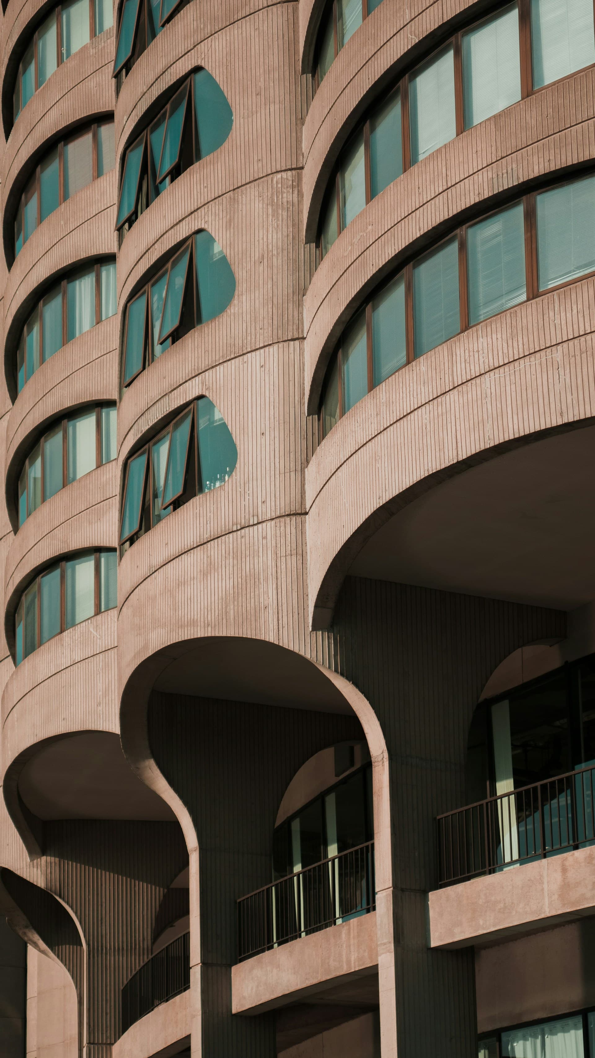 Curved concrete apartment facade with arched windows and balconies